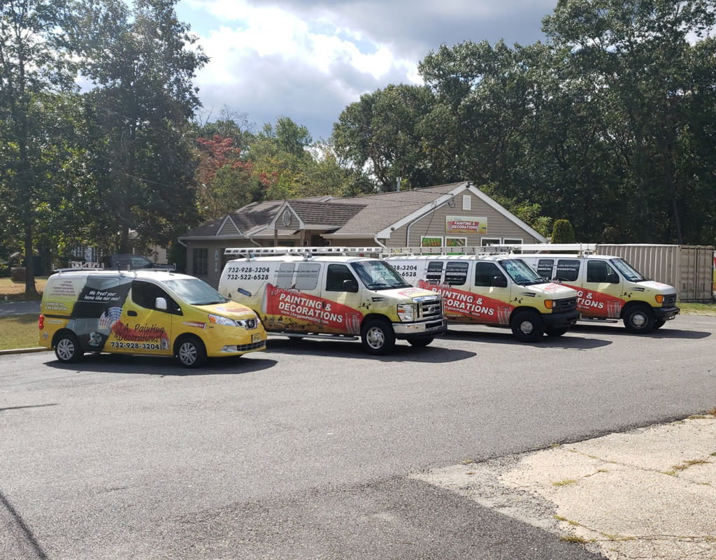 J.A. Painting & Decorations LLC service vehicles parked outside their office, showcasing their branding and contact information, reflecting their commitment to quality craftsmanship in painting and carpentry services.
